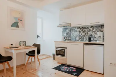 a kitchen with white cabinets and a table and a desk at Artiesta - 5 apartments in Sofia