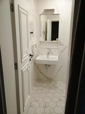 a white bathroom with a sink and a mirror at Luxury rooms 12-2 in Plovdiv
