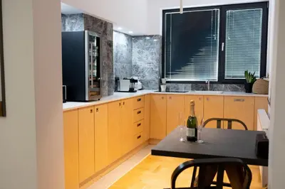 a kitchen with wooden cabinets and a table with a bottle of wine at Luxury room 12-3 in Plovdiv
