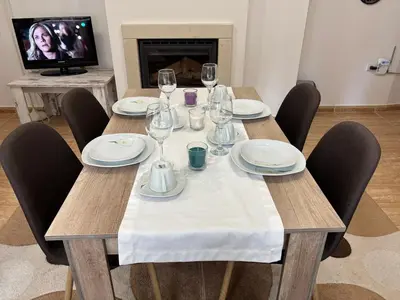 a wooden table with chairs and wine glasses on it at Апартамент за гости 4а26 Планинска Магия Grand Monastery Пампорово in Pamporovo