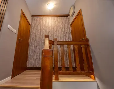 a stairway with a wooden railing and a door at Къща за гости В 12 и 5 in Dolna Banya