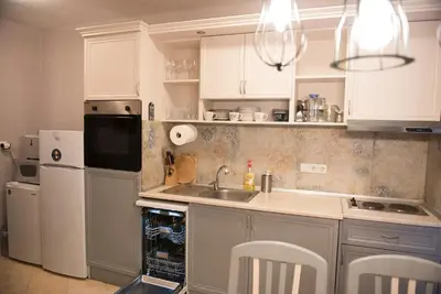 a kitchen with white cabinets and a sink and a refrigerator at Къща за гости В 12 и 5 in Dolna Banya