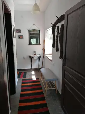 a hallway with a door and a stool and a rug at Каменната къща in Borowo