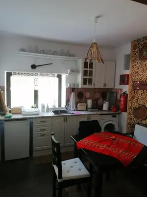 a kitchen with a table with a red table cloth on it at Каменната къща in Borowo