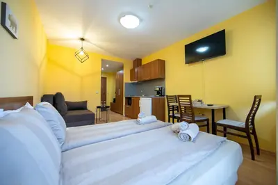 a bedroom with a large white bed and a kitchen at Studio Villa Park 325 in Borovets