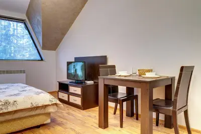 a bedroom with a table and a bed and a television at Студио Ая- Смолянски езера in Smolyan