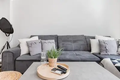 a living room with a gray couch with remote controls at Sophisticated Gem in the Heart of Sofia in Sofia