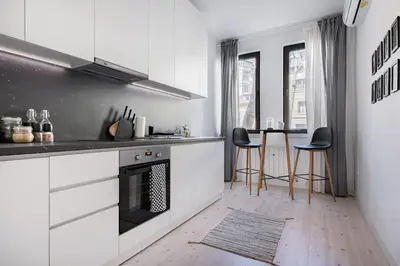 a kitchen with white cabinets and a table with chairs at Sophisticated Gem in the Heart of Sofia in Sofia