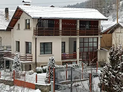 a house with a fence in the snow at Detached Guest House Рилски кът Маджаре in Madzhare