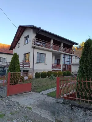 a large white house with a red gate at Detached Guest House Рилски кът Маджаре in Madzhare
