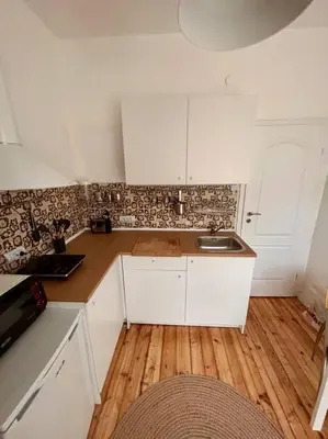 a kitchen with white cabinets and a wooden floor at Chic Urban Retreat in Sofia