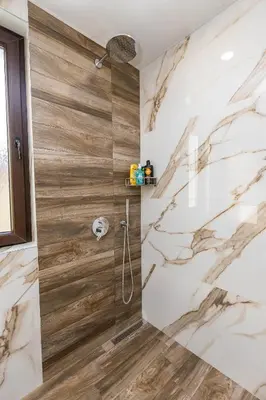 a bathroom with a shower with marble walls at Apartment Betty in Sandanski