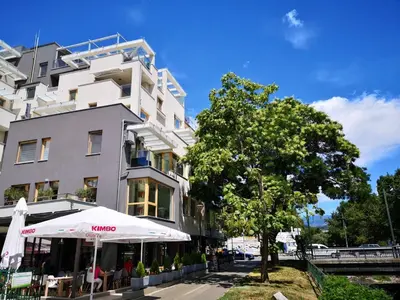 a white building with an umbrella next to a tree at Sky Apartments in Blagoevgrad