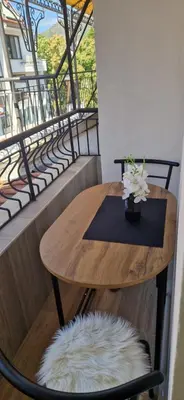 a wooden table with a vase of flowers on a balcony at Black and White Apartment in Karlovo