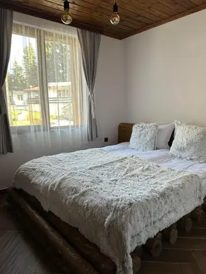 a bed in a bedroom with a large window at CHALET ELEVEN in Dospat