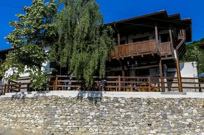 a house with a tree in front of a stone wall at Delchovski Han in Delchevo