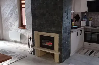 a living room with a fireplace in a kitchen at АПАРТАМЕНТ WISH in Pamporovo