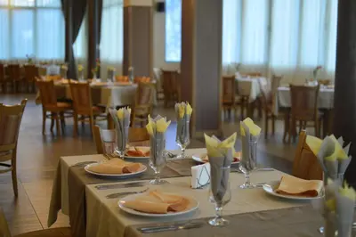 a table with plates of food on it in a restaurant at Хотел Дикас in Smolyan