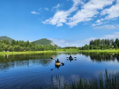 two people kayaking on a lake on a sunny day at SPA Hotel Daffi in Smolyan