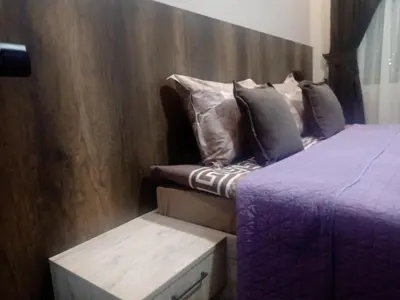 a bedroom with two beds and a wooden wall at Кръчмъ При Байката апарт in Teteven