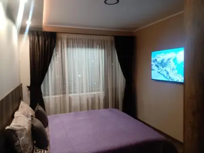a bedroom with a bed and a tv on the wall at Кръчмъ При Байката апарт in Teteven