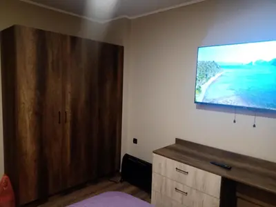 a bedroom with a tv and a wooden cabinet at Кръчмъ При Байката апарт in Teteven