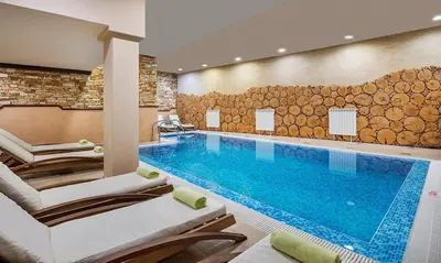 a swimming pool in a hotel room with chairs and a pool at Royal Park Bansko premium in Bansko