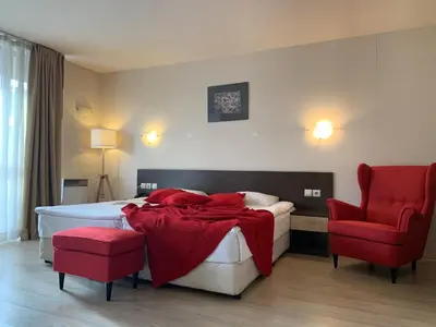 a bedroom with a bed and two red chairs at Banderitsa Apartment 2 in Bansko