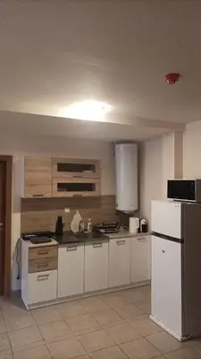 a kitchen with white cabinets and a white refrigerator at Bron's Suite in Pamporovo