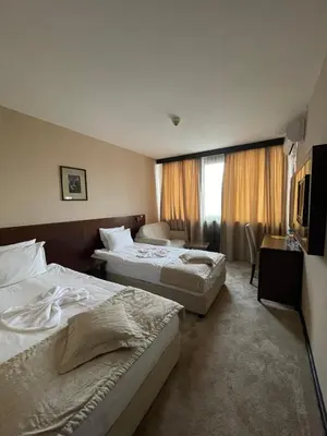 a hotel room with two beds and a window at Хотел Ботевград in Botevgrad
