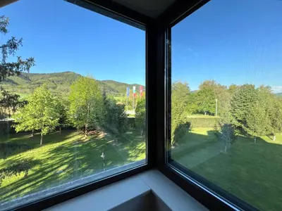 a window with a view of a green yard at Pravets Lake Panorama Apartments in Pravets