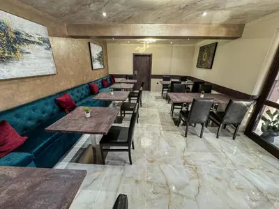 a restaurant with wooden tables and a blue couch at Стоичковата къща гр. Стрелча in Strelcha