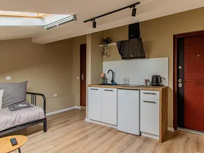 a kitchen with white cabinets and a couch in a room at Skyline Studio - Sofia Center in Sofia