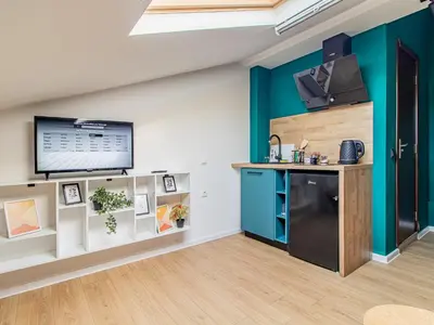 a kitchen with a black refrigerator and a tv on a wall at Eagle's Nest - Sofia Central Studio in Sofia