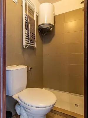 a bathroom with a white toilet and a light at Vazov Loft - Central Sofia Studio in Sofia