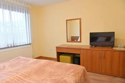 a bedroom with a television and a dresser with a mirror at Къща за гости ГРАНИТ in Bansko