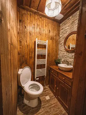a wooden bathroom with a toilet and a sink at Кътче in Leshten