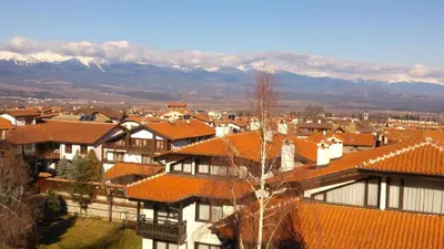 a group of houses with red roofs and mountains at Ioannis Apartment Bansko in Bansko