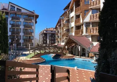 a bridge over a swimming pool next to some buildings at Belvedere Holiday Club SPA&POOL Private Apartments in Bansko