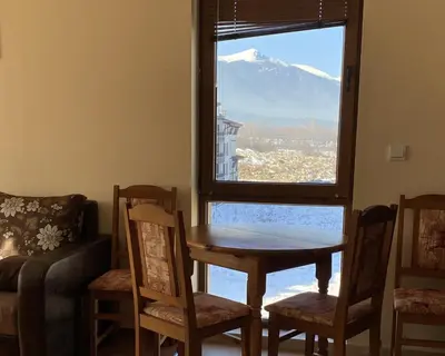 a table and chairs in a room with a window at Belvedere Holiday Club SPA&POOL Private Apartments in Bansko