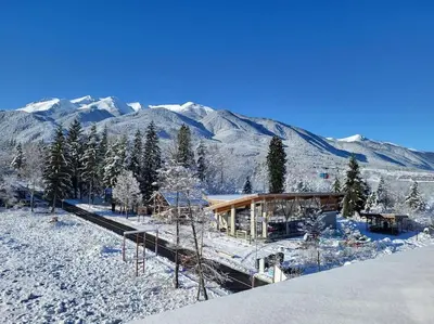 a house in the snow with mountains in the background at KS Rooftop 180° in Bansko