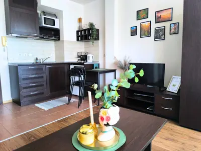 a living room with a kitchen and a table with flowers at Happy Stay 100mfrom Gondola with free Bottle of Wine and free Parking in Bansko