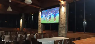 a large screen in a room with tables and chairs at Alpine Garden Hotel (Trayanovi Dvori) in Simitli