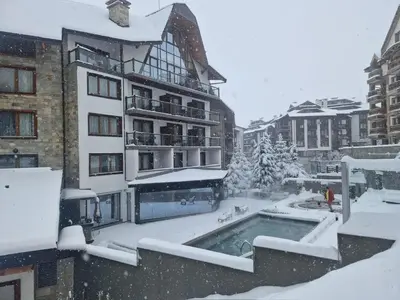 a building with a swimming pool in the snow at Family Luxury Private Apartments in 4 star SPA Resort St Ivan Rilski, Bansko in Bansko
