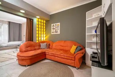 a living room with an orange couch and a television at Cozy Apartment near Vitosha Street by Flat Mаnager in Sofia