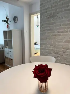 a red rose in a vase on a white table at Family friendly downtown apart in Sofia
