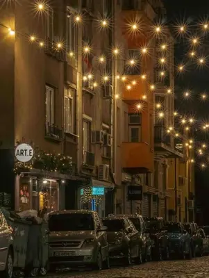 a street with cars parked in front of buildings at night at Family friendly downtown apart in Sofia