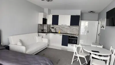 a living room with a couch and a table and a kitchen at Димоти Апартхотел in Sofia
