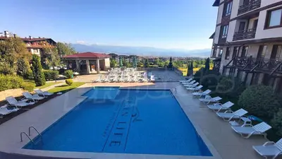 a swimming pool with lounge chairs and a building at Spacious luxury studio with mountain view - SPA available in Bansko