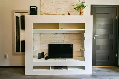 a white entertainment center with a television in a living room at Neofit Rilski Apartment (near Vitoshka street) in Sofia